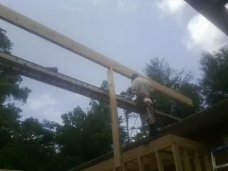 Carpenter setting a ridge beam over a new addition frame — Ice Dam Removal by Roofing Brothers in Woodruff