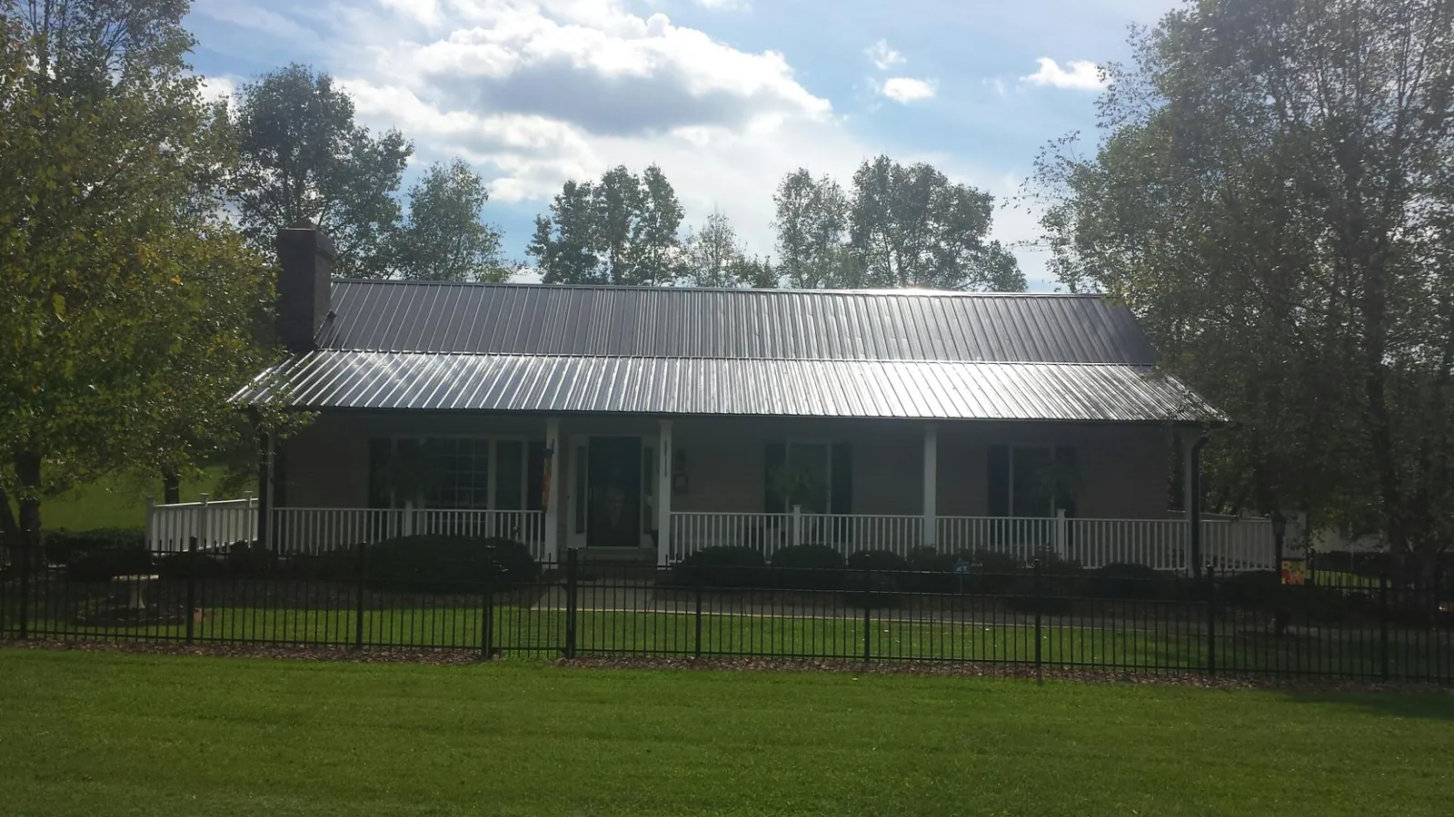 Gray metal roof on a brick ranch with a full width front porch — Gutter Guard Installation work by our crew in Woodruff